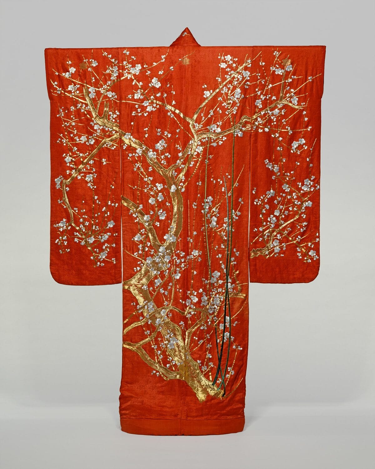 Red silk furisode with long hanging sleeves, embroidered with a gold-trunked plum tree in white blossom from hem to shoulder