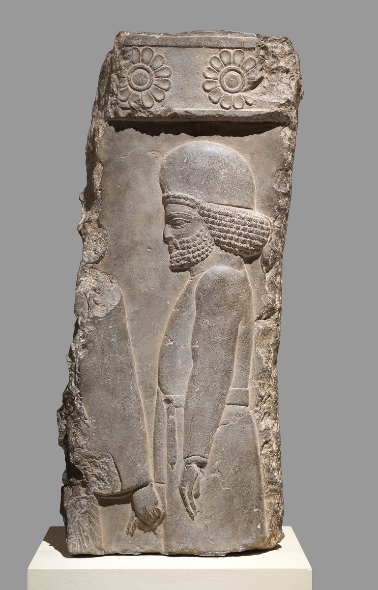 Limestone relief from Persepolis of a bearded man in a rounded cap and belted tunic walking in a procession