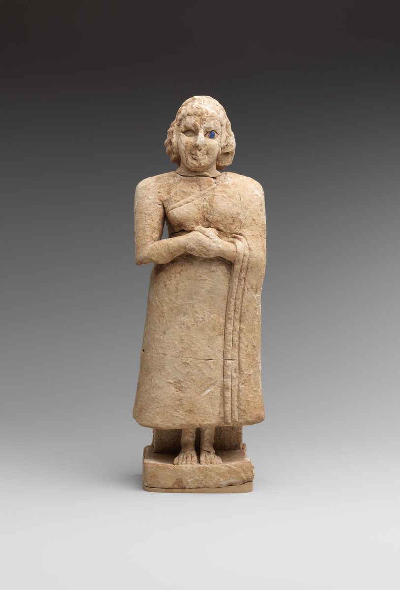 Sumerian limestone statue of a standing female worshiper, her garment draped over one shoulder