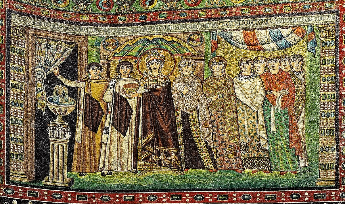 Empress Theodora in a long purple chlamys with figures embroidered at the hem, a jeweled crown and a broad pearl collar, holding a gold cup, surrounded by court women in patterned silk mantles and veils