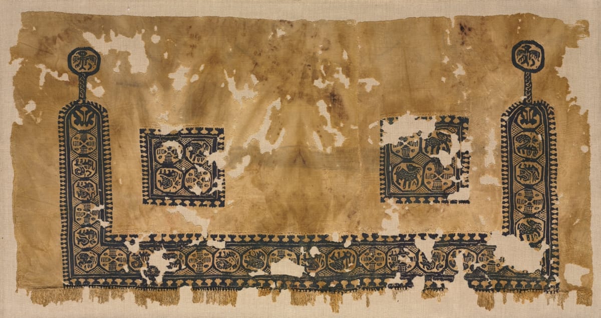 Lower half of a linen tunic decorated along the hem with a dark blue band of roundels containing animals and baskets, with two square panels above