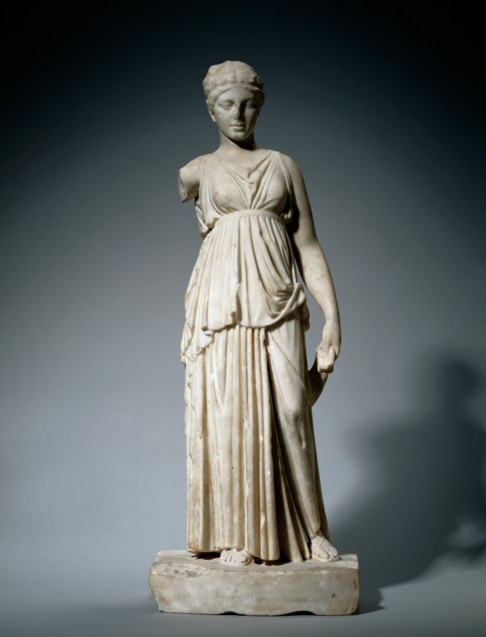 Marble statuette of a woman in a long belted chiton with a deep overfold, standing with one knee bent and holding a sash