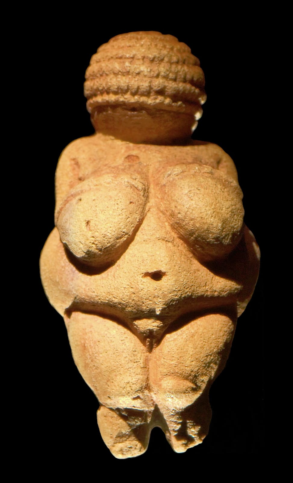 Front view of the Venus of Willendorf, a small rounded limestone figurine whose head is covered by bands of carved rows