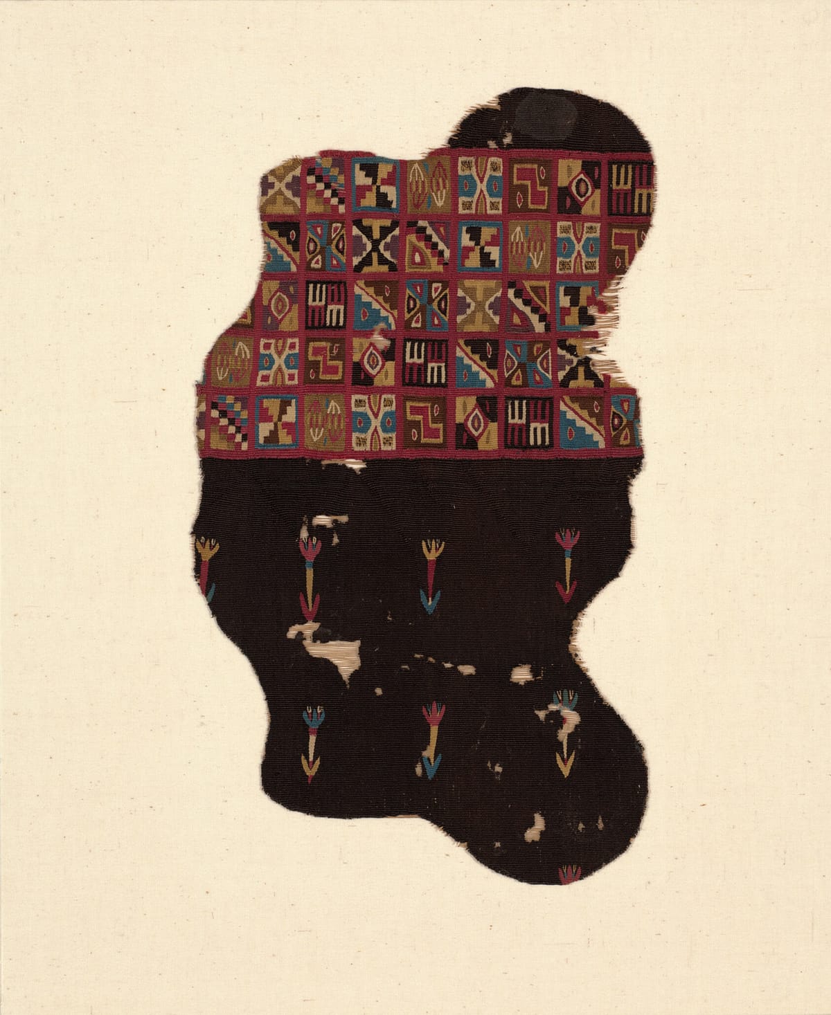 Fragment of a colonial Andean man's tunic, with a band of colorful tocapu squares above a dark field scattered with small red and blue flowers