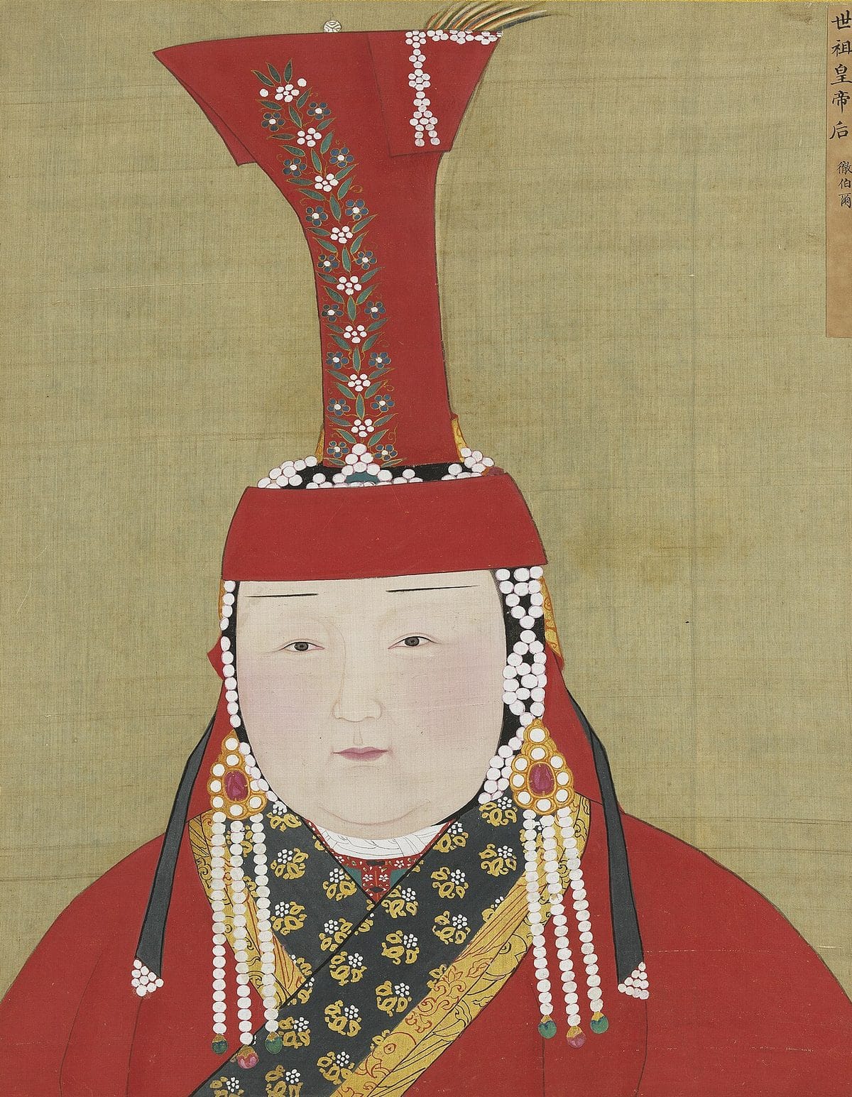 Portrait of a Mongol empress in a red robe with a black and gold patterned collar, wearing a tall red boghtaq headdress decorated with pearls and flowers