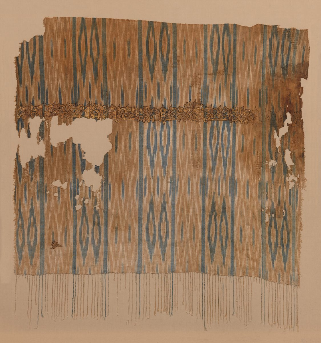 Fragment of a striped blue and brown ikat-dyed cotton shawl with a gilded inscription band, Yemen