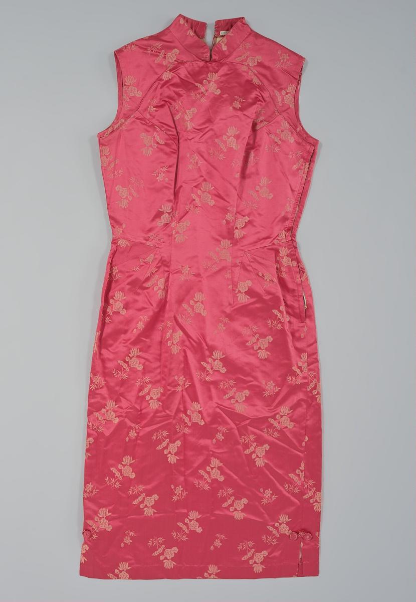 Sleeveless pink-red satin qipao with a woven floral pattern, mandarin collar, curved front seams, and short side slits, photographed flat