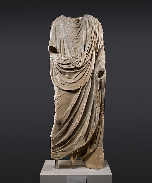 Headless marble statue of a man in a long toga draped over his left shoulder, with a deep curved fold across the front